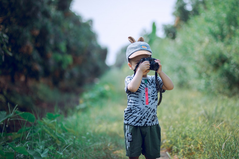 boy-using-camera-near-green-leaf-plants-1374510